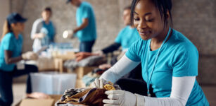 black female volunteer packing clothes in donation boxes while working at community center.