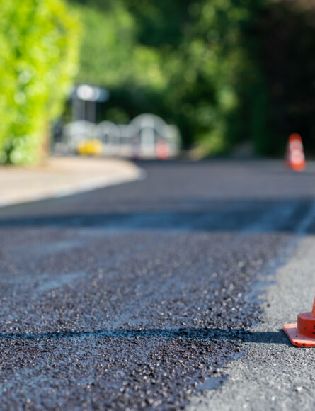 construction cones marking part of road with a layer of fresh asphalt.